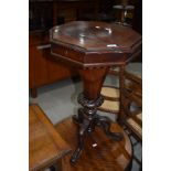 A Victorian octagonal sewing table having fitted interior, lock removed, heavily carved base