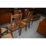 A set of four early 20th century golden oak dining chairs having rail backs, later dralon