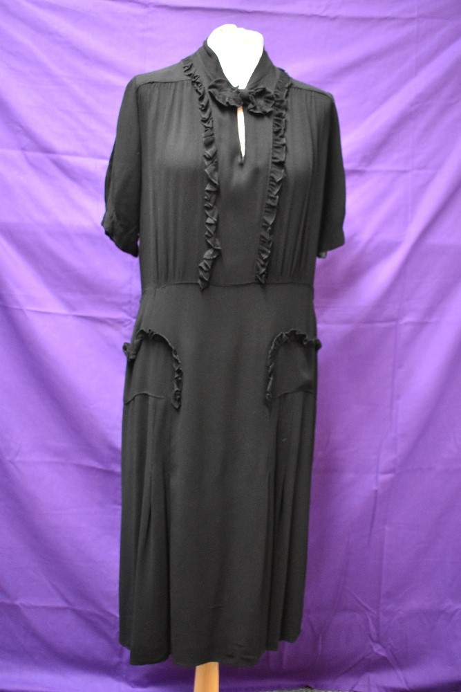 A 1940s black crepe dress with frilled details,bow to neckline and tucks to skirt, around a medium