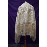 A large vintage cream shawl Having extensive embroidery and fringed edges.
