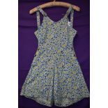 A 1940s cotton playsuit having bright floral print, buttons to both sides and buttons to front of