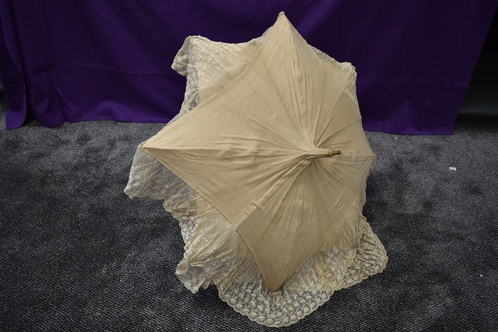 An early 20th century cream slub silk parasol with an abundance of tulle lace surrounding the