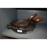 A selection of wooden handled cast iron skillet frying or sauce pans