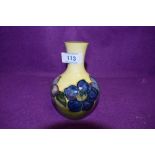 A Moorcroft vase having pale yellow ground and blue hued floral design.