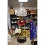 A large standing Victorian oild lamp having twisted brass stem cranberry glass well and etched shade