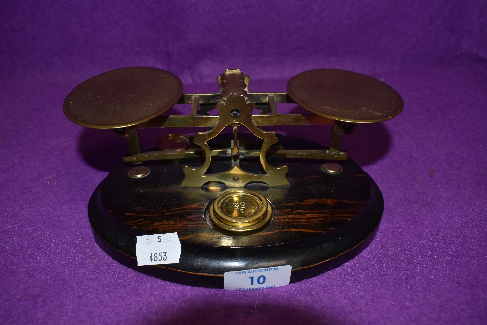 A set of brass apothecary scales on wooden mount with some weights.