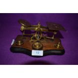 A set of brass apothecary scales on wooden mount with some weights.