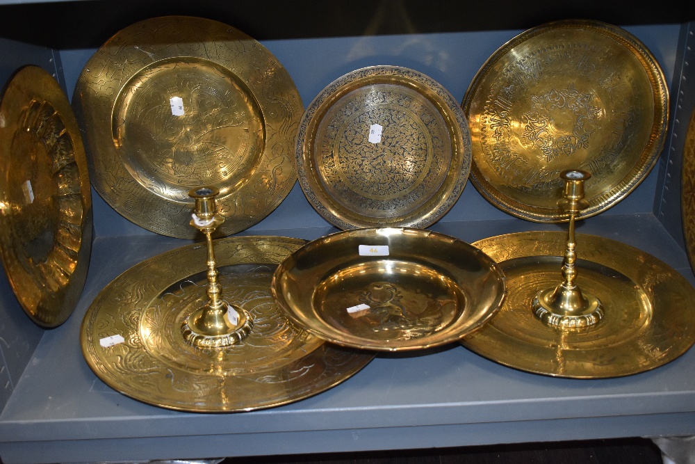 A pair of well cast brass candle sticks having knopped stems and a selection of various brass plates