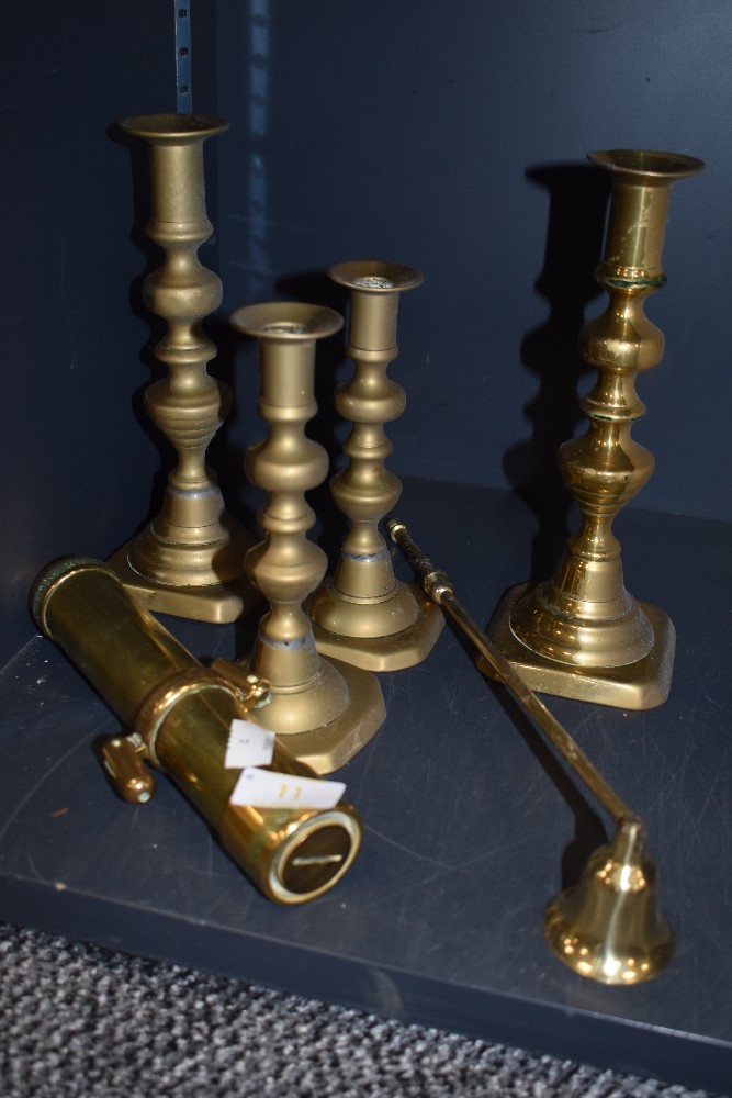 Four brass candle stick holders,a snuffer and a Brass maritime torch possibly a divers torch 'The