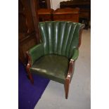 A vintage green leather or rexine fan back armchair on wooden frame