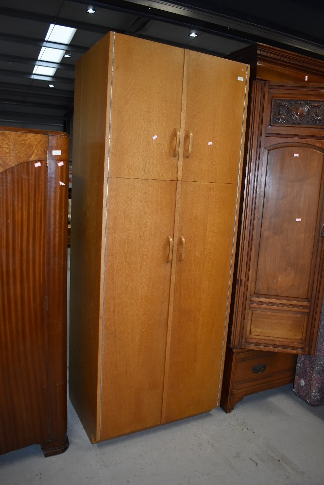 An early to mid 20th Century golden oak and sapele double cupboard, in the Gomme/G Plan style,