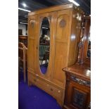 A late 19th/early 20th Century golden oak wardrobe having oval mirror door, width approx. 118cm