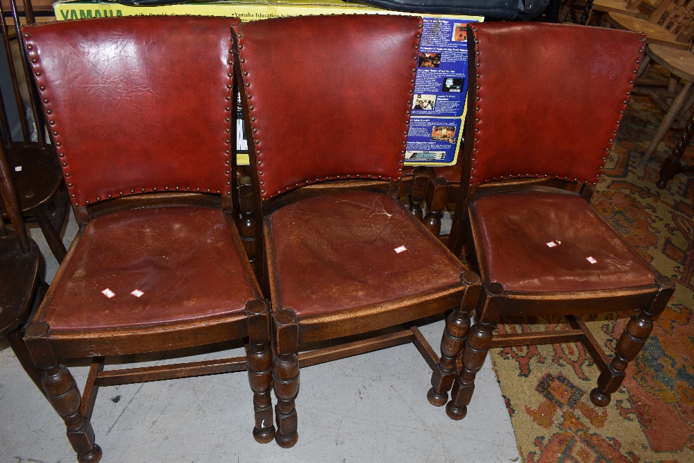 A set of six early 20th Century oak frame dining chairs having red leather seats and backs