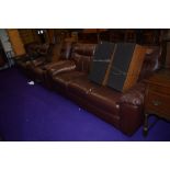 A modern brown leatherette or bycast lounge suite comprising two three seater settees and one chair