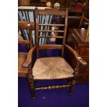 A traditional stained frame Lancashire or similar spindle back carver chair having rush seating