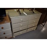 A cream bedroom chest of four by four drawers, width approx. 110cm
