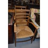 A pair of vintage ladder back carver chairs, having rush seats, possibly teak