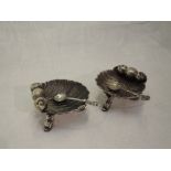 A pair of Victorian silver salts in the form of scallop shells on trefoil mythical fish feet,