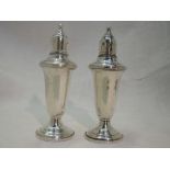 A pair of white metal oversized pepperettes stamped Empire sterling of urn form having clear glass