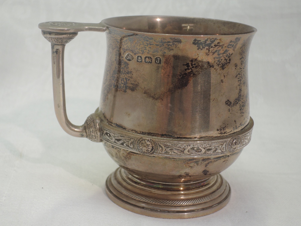 A silver christening mug bearing monogram to front and date to base with Celtic style handle and