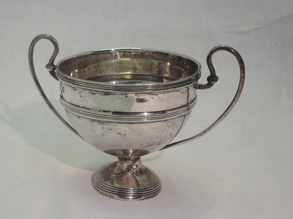 A small Edwardian silver trophy bowl of traditional form having loop handles and reeded