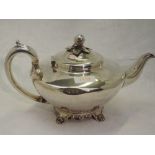 A Georgian silver teapot of plain compressed circular form having bracket feet, scroll handle and