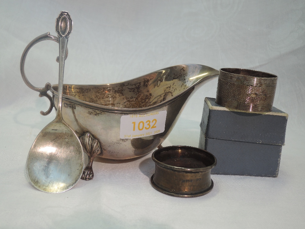 An Edwardian silver sauce boat of plain form having trefoil paw feet, loop handle and reeded rim,