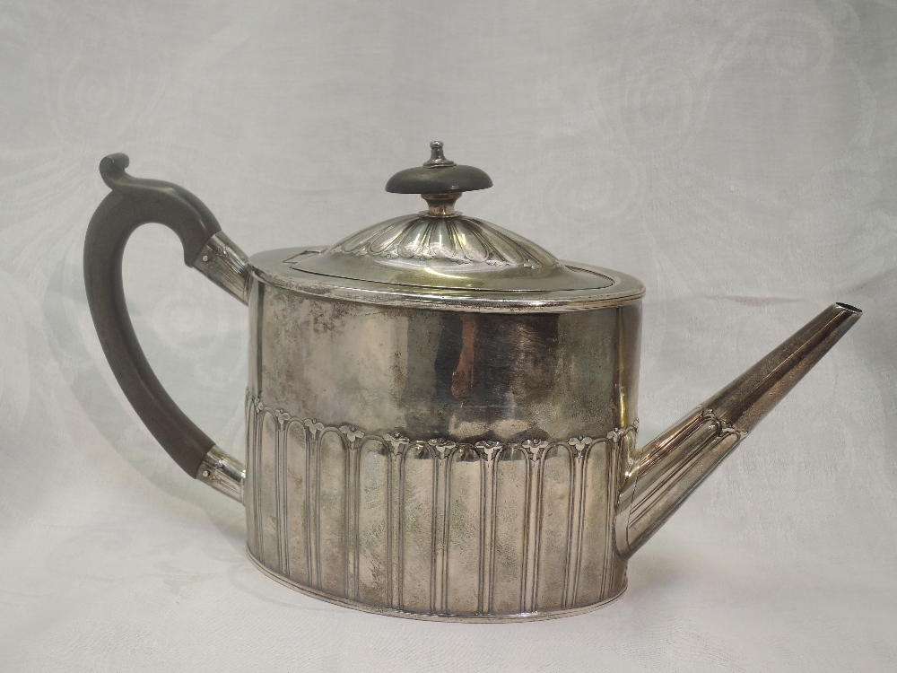 A Georgian silver teapot of drum form having gadrooned decoration and fruitwood handle, bearing