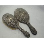 A Victorian silver brush and hand mirror having heavily embossed mask, bird and scroll decoration,