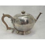 A silver teapot of plain circular form having fruit wood handle and knop, engraved decoration to lid