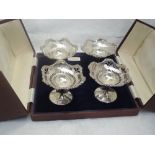 A cased set of four small silver tazzas having pierced and moulded decoration to bowls on weighted