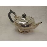 A silver breakfast teapot of plain squat circular form having hard wood handle, pedestal foot and