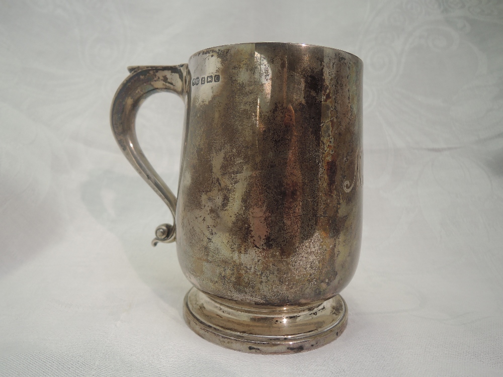 An Edwardian silver tankard of plain baluster form on circular pedestal foot with thumb rest loop