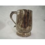 An Edwardian silver tankard of plain baluster form on circular pedestal foot with thumb rest loop