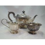 A silver three piece matched tea set of circular form having facetted decoration, fruitwood handle