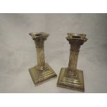 A pair of Edwardian silver candlesticks of Corinthian column form having removable sconces and