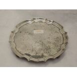 A silver card tray of plain form having monogram to centre, pie crust rim and quadrafoil scroll