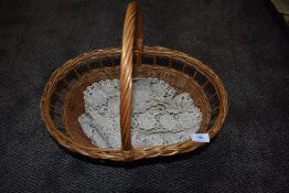 A wicker basket and a crotchet table runner.