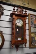 A wooden cased chiming wall clock having carved details and finials to top.