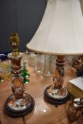 A pair of ceramic table lamps with shades having fruit design and gilt detailing.