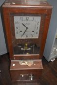 A vintage mahogany cased clocking-in machine, with square dial above the pendulum, mechanism and