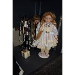 Two dolls with stands, a selection of necklaces and a mirrored photo frame.
