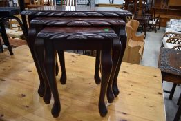 A reproduction mahogany effect nest of three tables