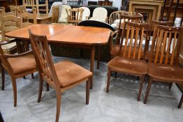 A vintage teak extending dining table and six (four plus two) rail back dining chairsm labelled G