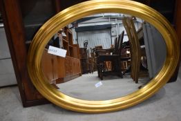 A oval gilt framed hall mirror having bevel edged glass