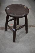 A well used traditional kitchen pine stool painted brown