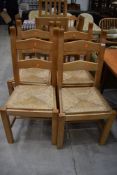 A set of four modern beech ladder back chairs having rush seats