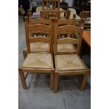 A set of four modern beech ladder back chairs having rush seats