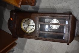 An Edwardian style oak cased wall mounted clock with polished dial