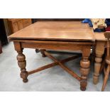 An early to mid 20th Century oak drawer leaf table on cross stretcher and bulbous column legs,